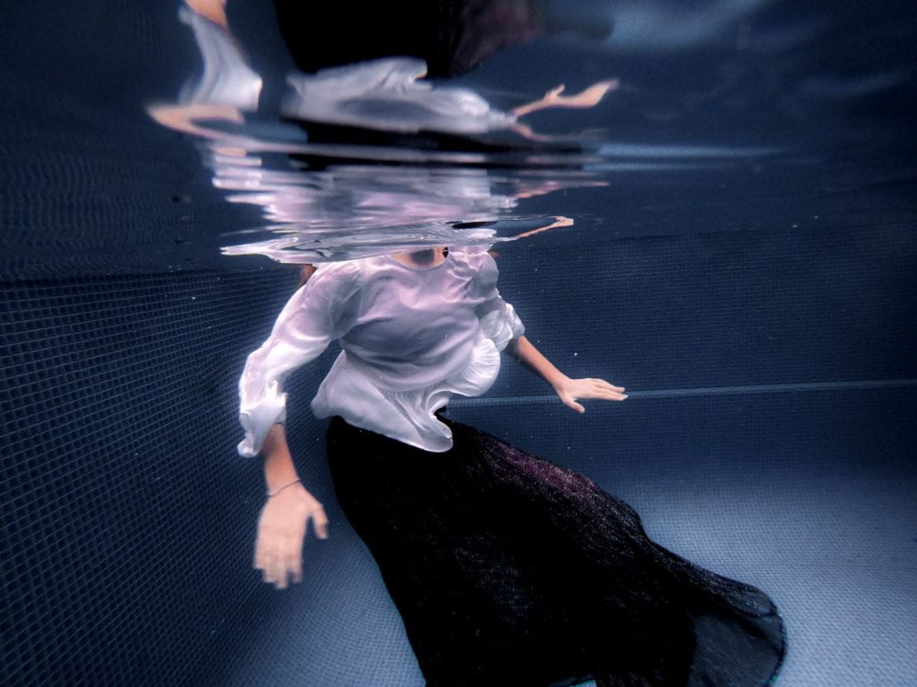 Person underwater, their head out of shot, but above water