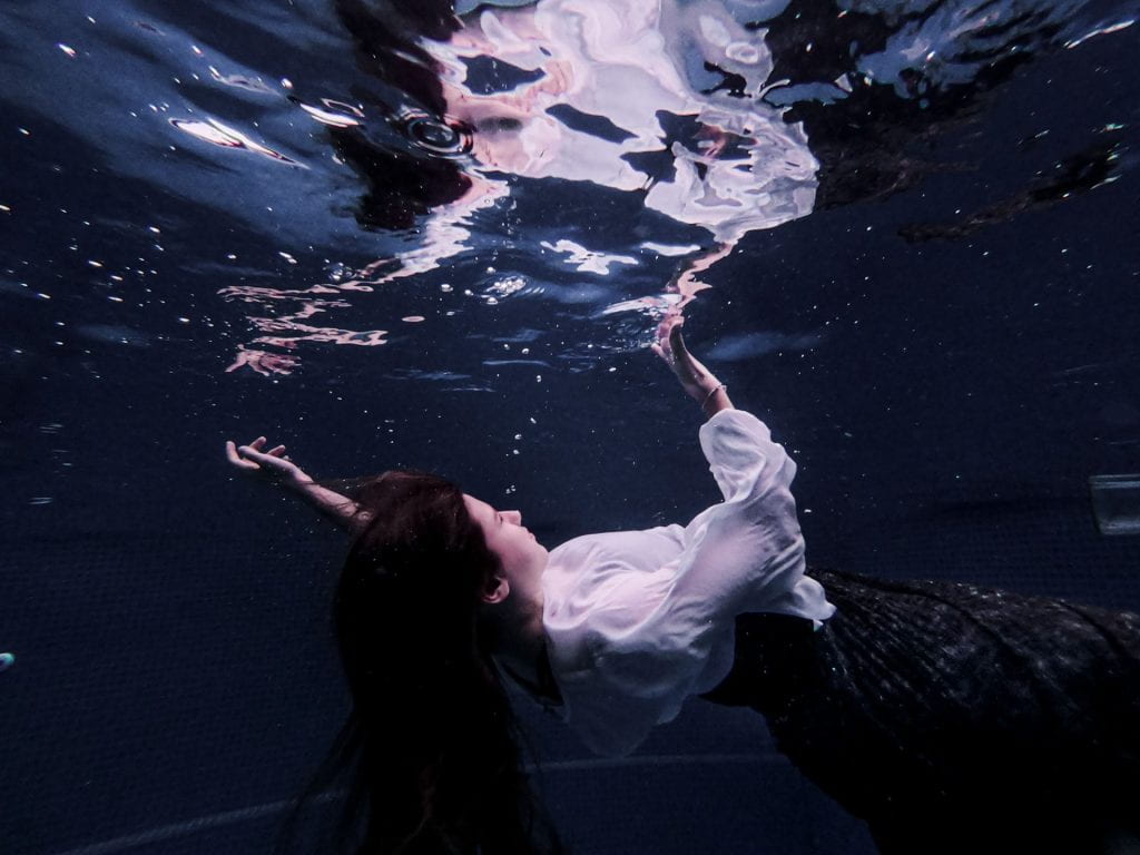 Person underwater, their reflection on top