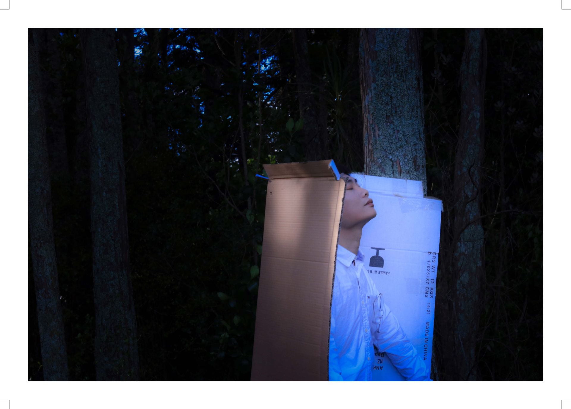 Person outdoors, leaning against cardboard